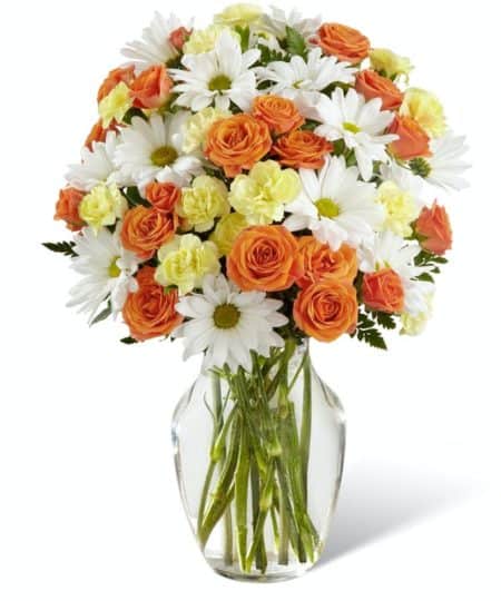 It's so easy to send some smiles to a friend, colleague or loved on today. This affordable bouquet features a sweet combination of orange spray roses, yellow mini carnations and white daisies. Flowers are arranged in a clear glass vase with some added greenery for a perfect light and delightful touch.